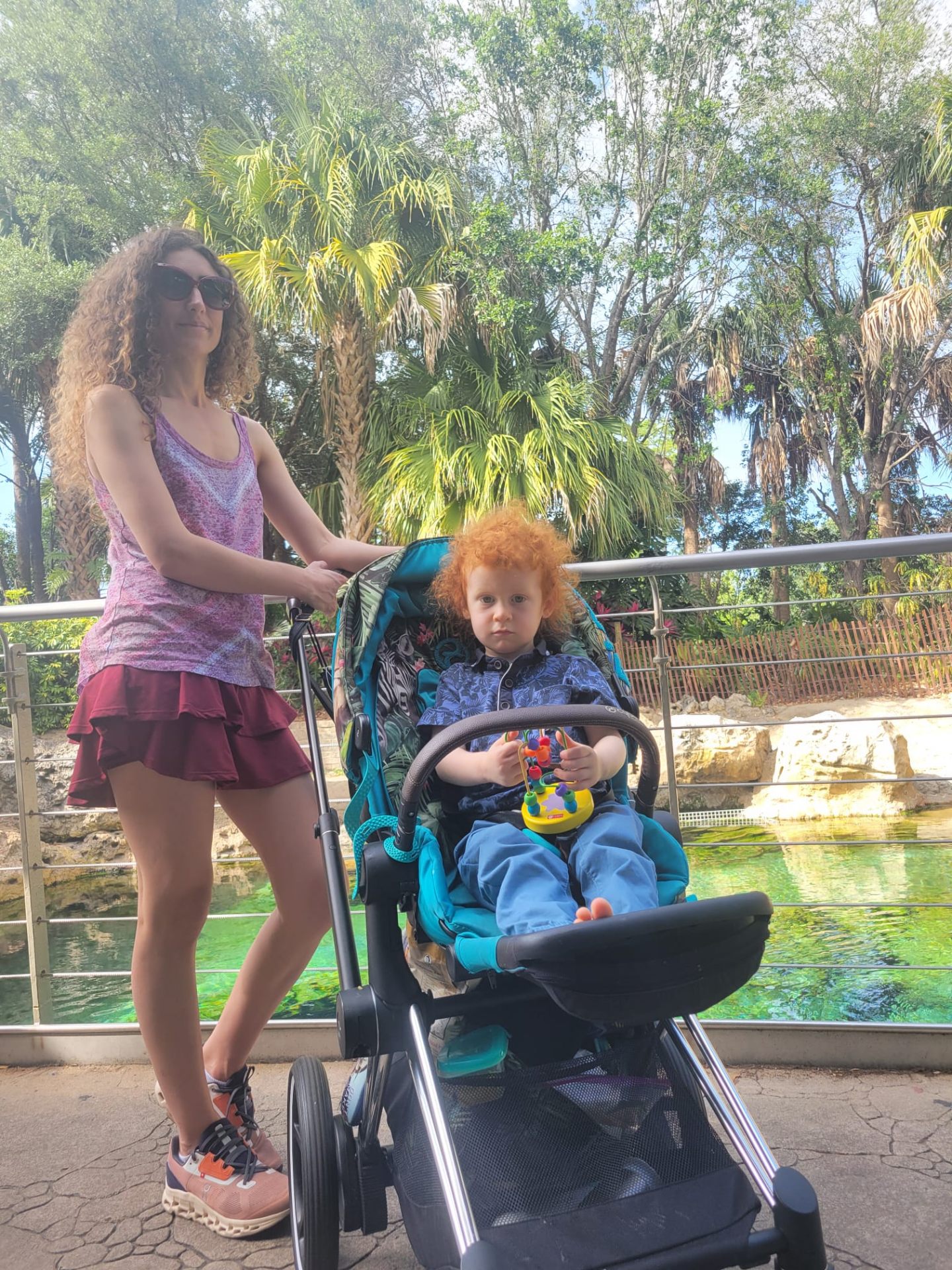 Mama Mimi on a field trip with a child in a stroller by a tropical lagoon