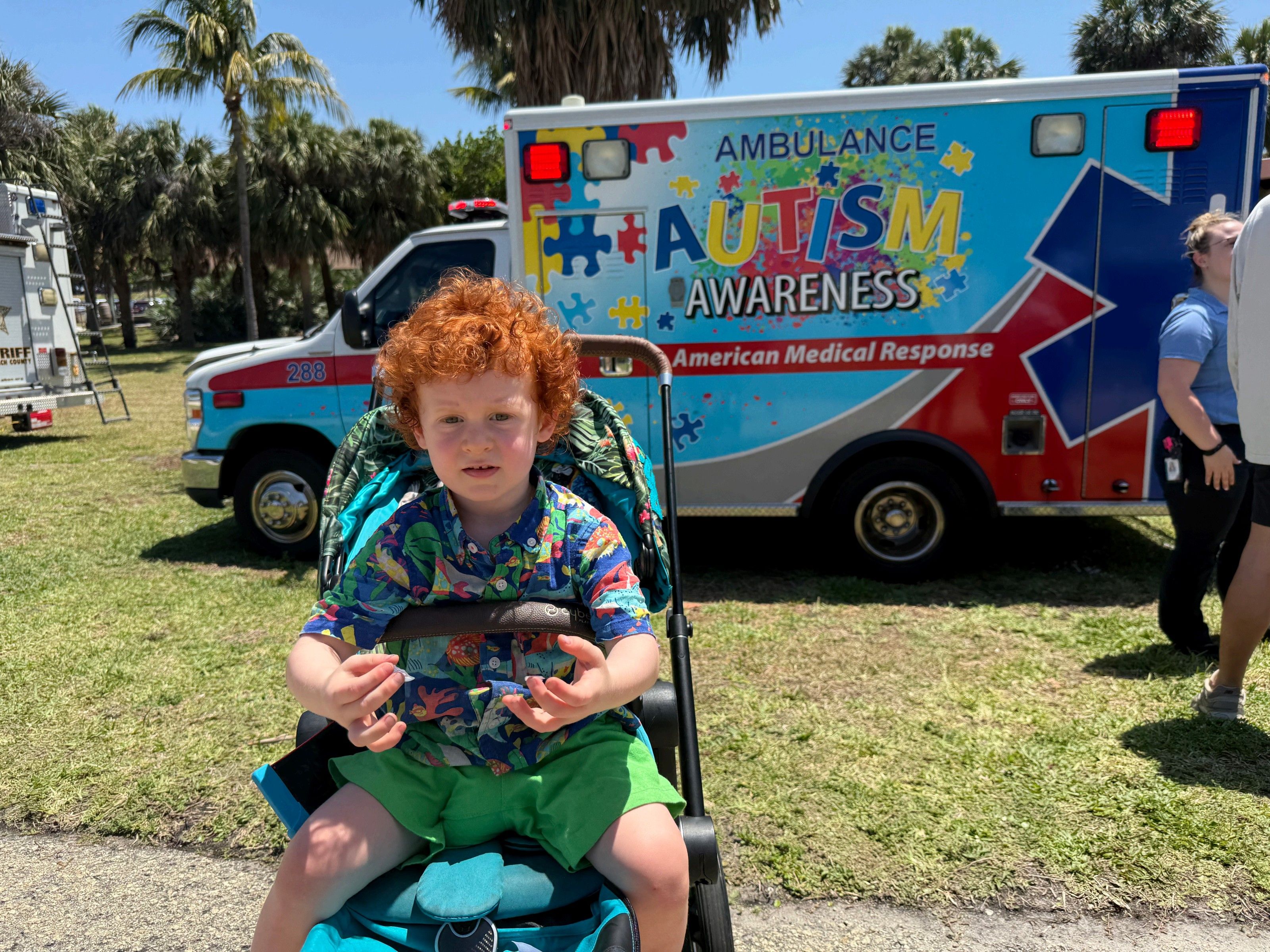 Child in a stroller in front of an ambulance with Autism Awareness design