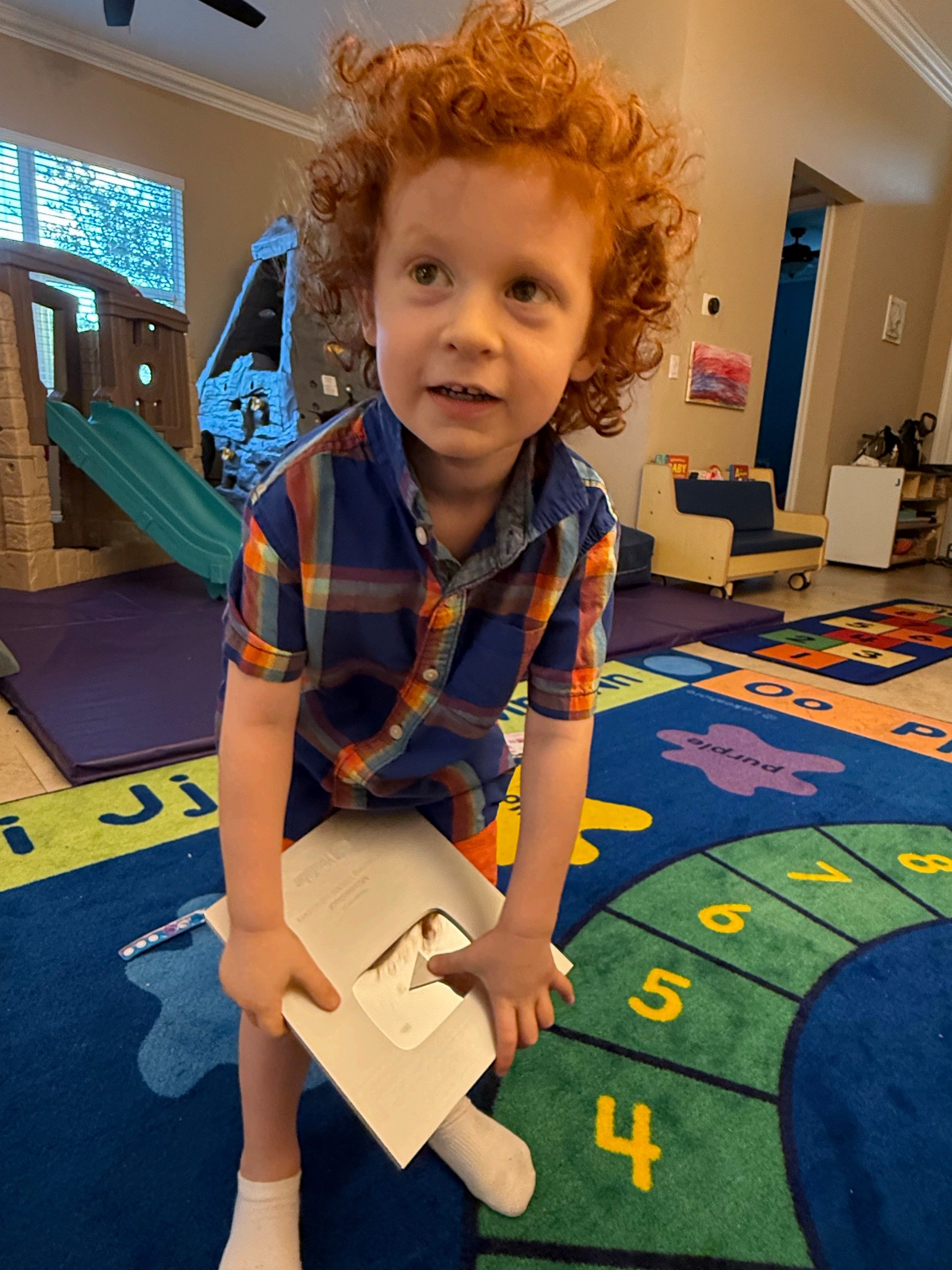 Child holding YouTube Silver Play Button award in a playroom